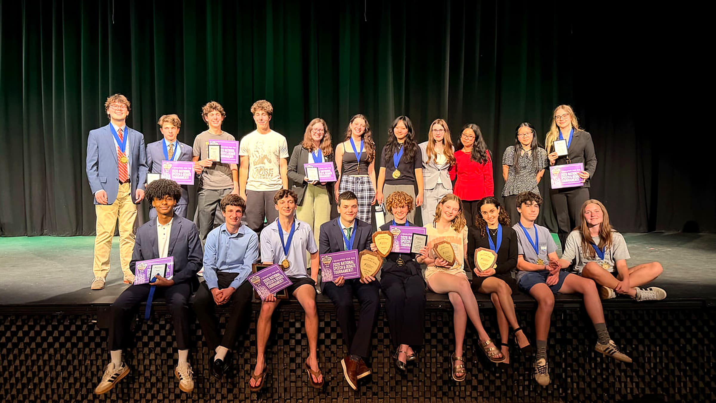 Myers Park Speech and Debate national qualifiers on stage with their awards